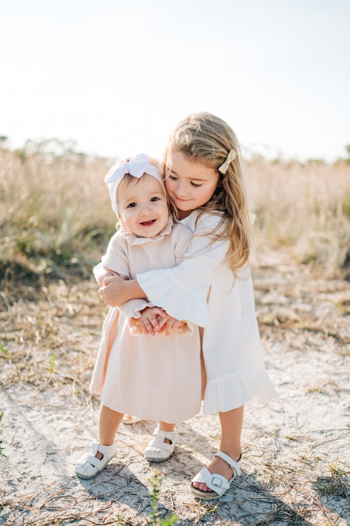 Sisters hugging during South Florida field family session.