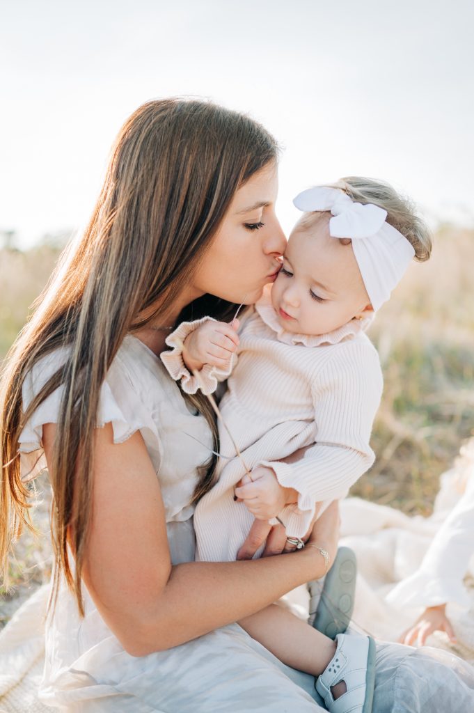 Mom kissing daughter's cheek at South Florida field family session.