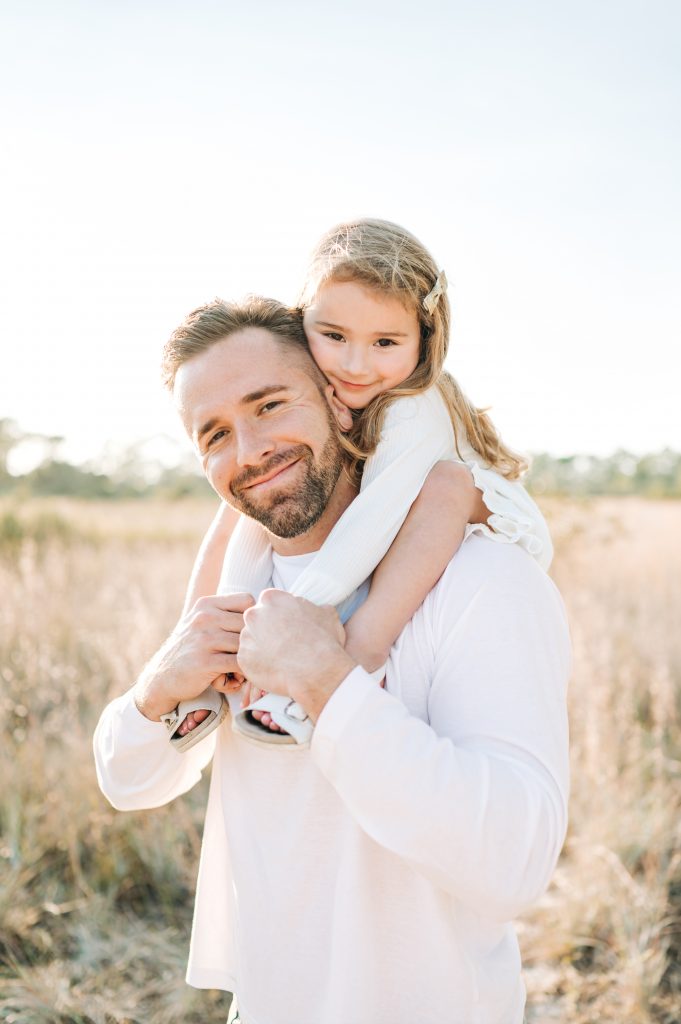 Daughter on dad's shoulder during South Florida field family session.